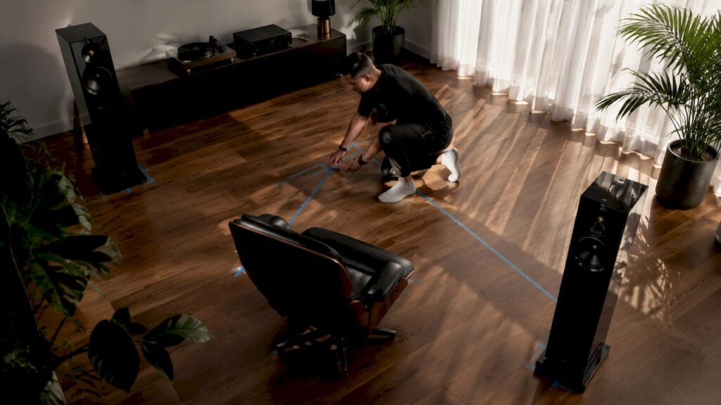 Man measuring speaker placement in bedroom