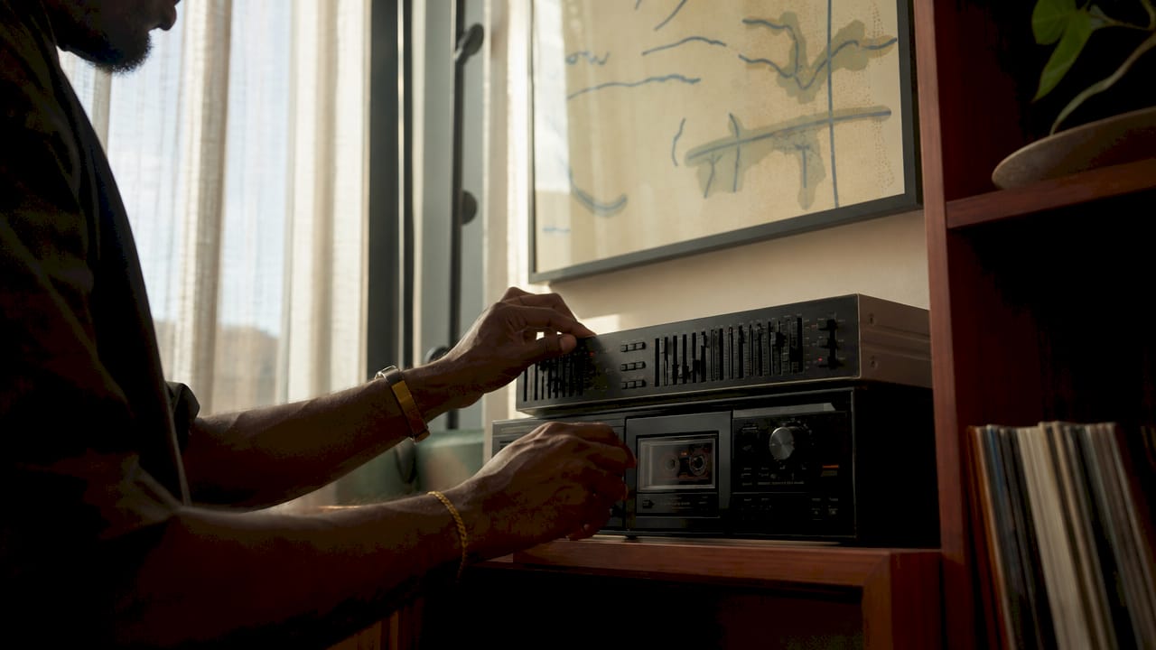 Hands adjusting stereo with Brian Eno album nearby
