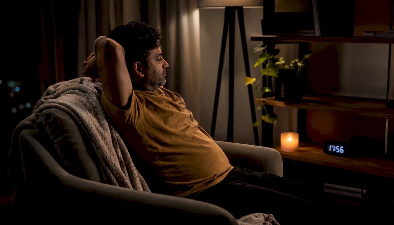 Man stretching in bedroom at night, calm atmosphere