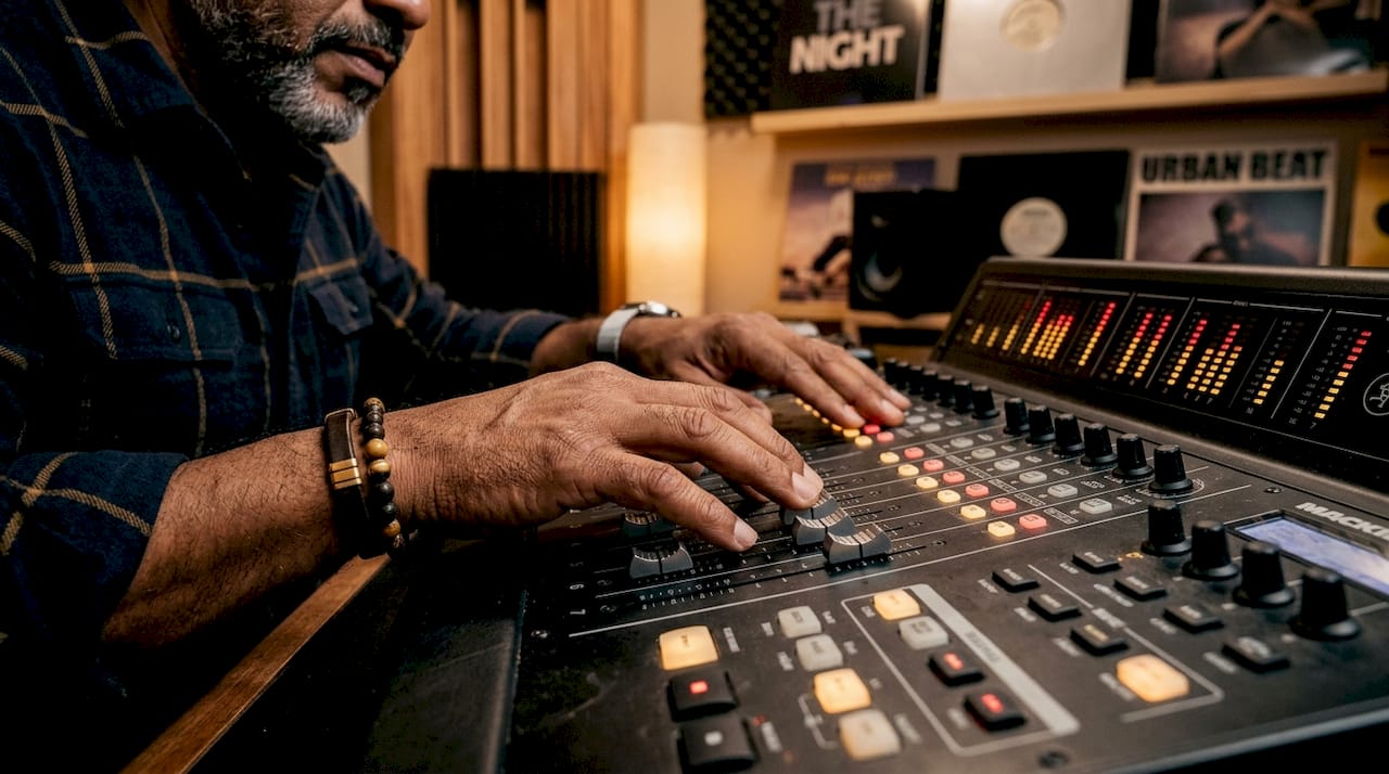 Hands adjusting audio mixer faders in recording studio