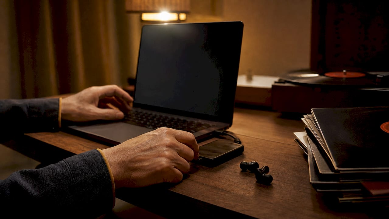 Hands connecting external SSD to desktop computer